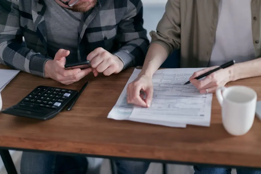 Two people filling in tax paperwork at a table