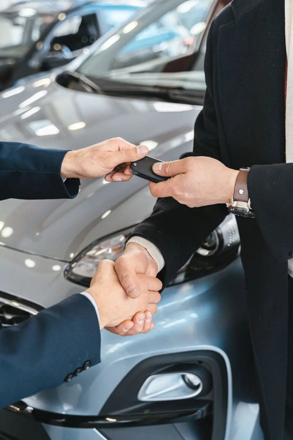 A handshake and car keys changing hands at a dealership, a deal that car dealer fees can change