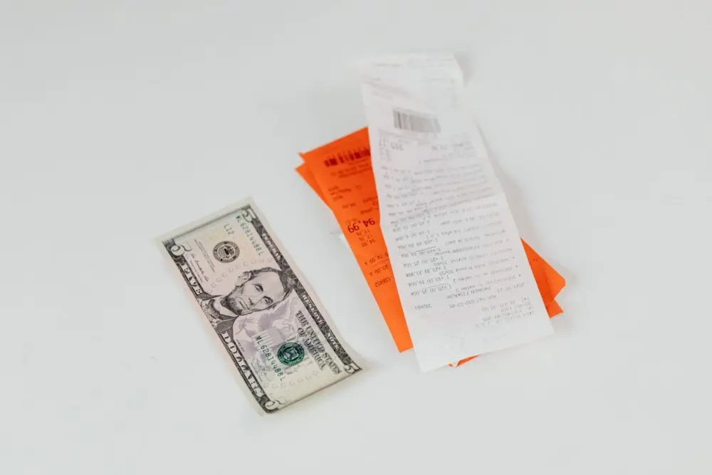 Shopping receipts and a dollar bill on a table, reflecting the consumer sentiment index and household budgets