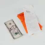 Shopping receipts and a dollar bill on a table, reflecting the consumer sentiment index and household budgets