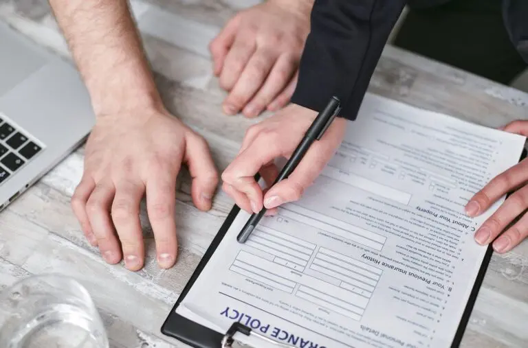 Hands signing an insurance policy document, a step to take only after checking health insurance ads against official sources