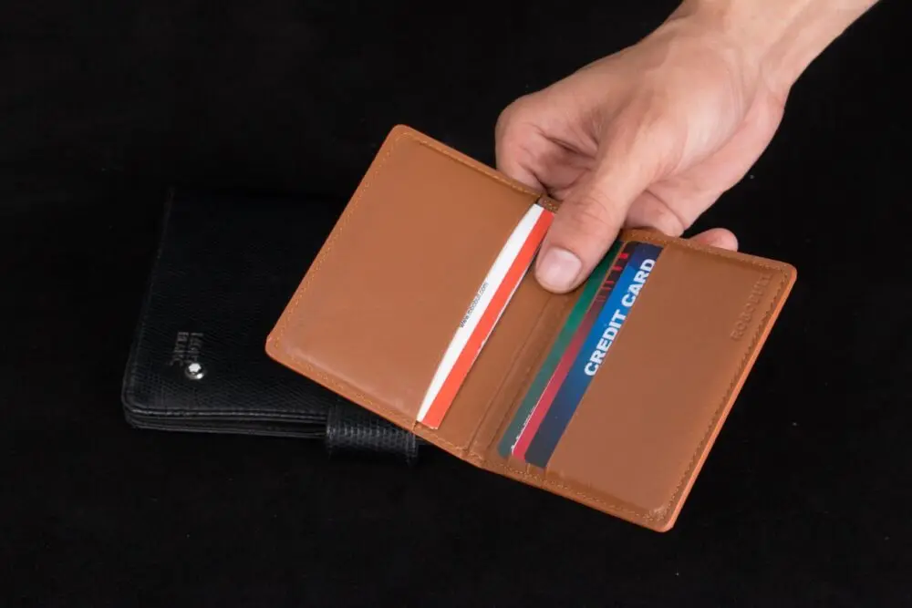 A hand holding a leather wallet with cards, the spending behind credit card earnings