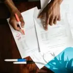 Hands highlighting credit report errors on financial documents at a desk