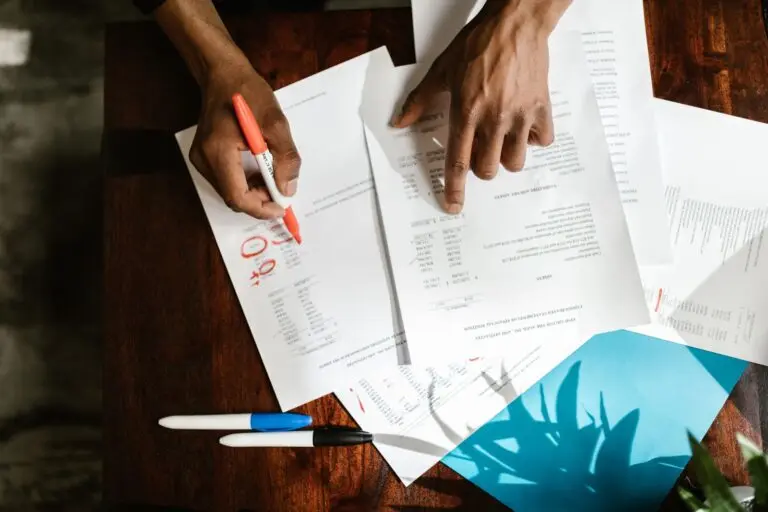 Hands highlighting credit report errors on financial documents at a desk