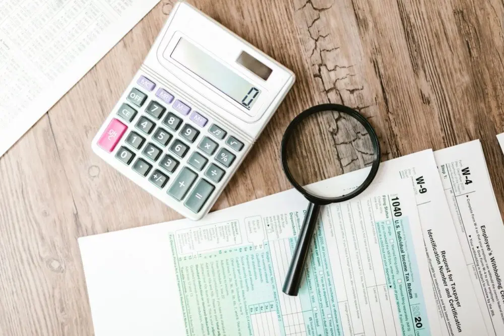 Tax forms laid out with a calculator and magnifying glass, used to check the 2027 tax brackets