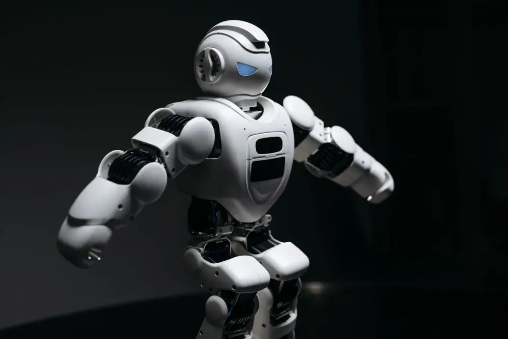 A silver and white humanoid robot standing against a dark background