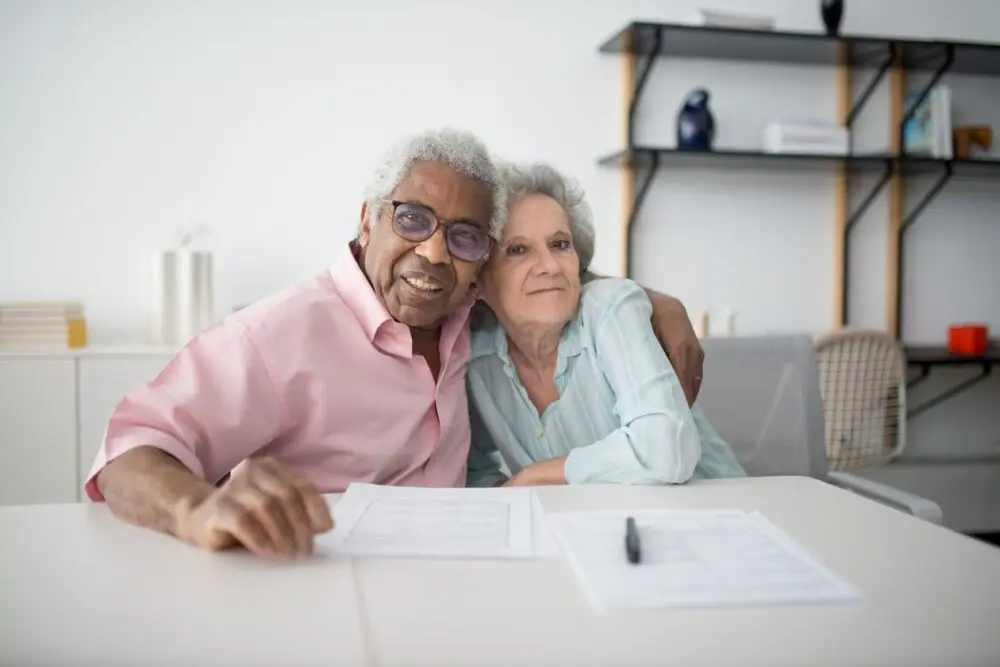 Older couple smiling over documents during Medicare open enrollment