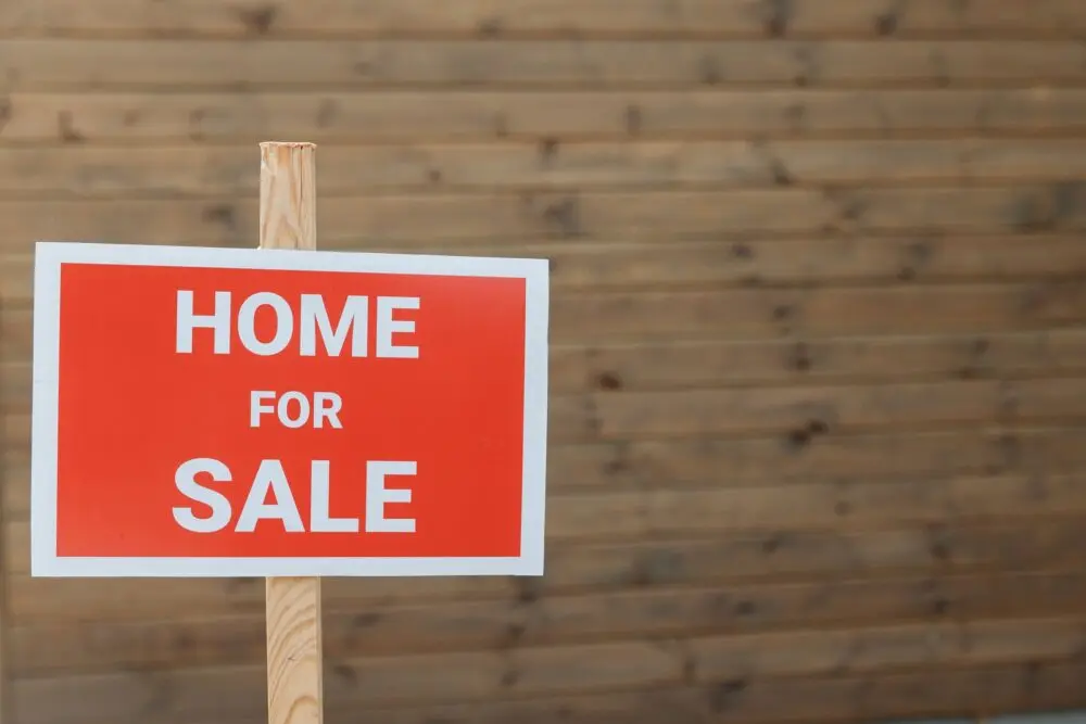 Red home for sale sign in front of a house, illustrating the slump in pending home sales