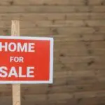 Red home for sale sign in front of a house, illustrating the slump in pending home sales