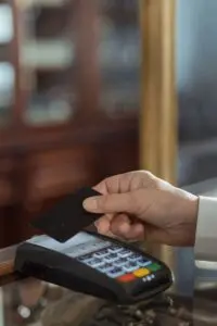 Hand holding a black credit card over a payment terminal, a Capital One earnings theme