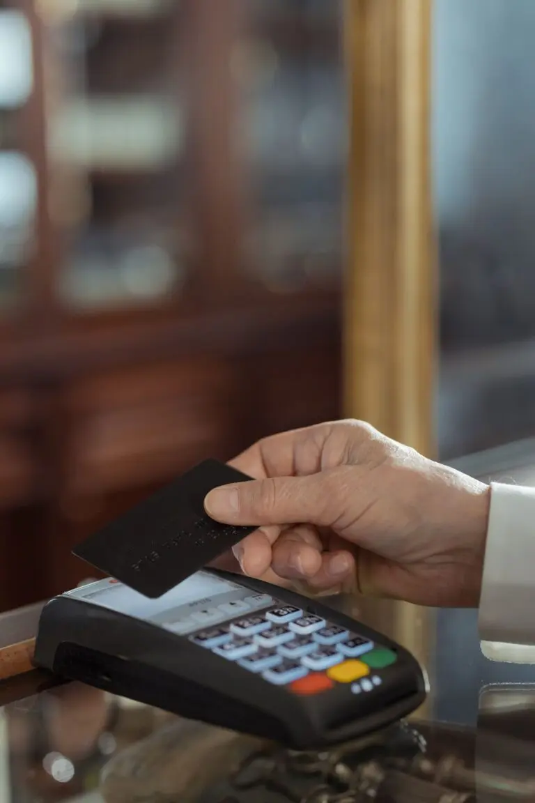 Hand holding a black credit card over a payment terminal, a Capital One earnings theme