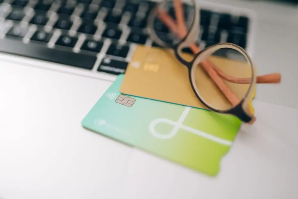 Credit cards and a magnifying glass on a laptop, checking before you freeze your credit