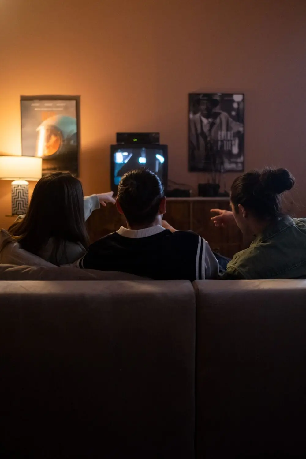 Three people seen from behind on a couch watching television in a living room