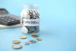 A glass jar of coins labeled Savings beside a calculator, illustrating the I bond rate decision